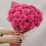 Bouquet of pink roses held by a person against a neutral background